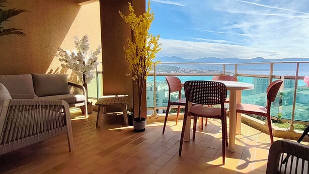 Un balcon avec un canapé, des chaises, une table et des plantes en pot.