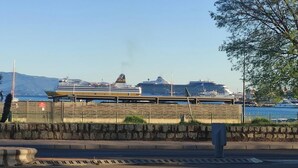 Une vue sur le front de mer, avec un navire de croisière amarré, un mur de pierre et des bateaux en arrière-plan.