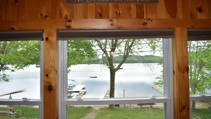 A wooden cabin with a sign reading 'No Charge for the View' and a view of a lake with a dock and boat. - Waterfront lake house with private beach and dock with hot  tub on Paradox Lake. (Schroon Lake)