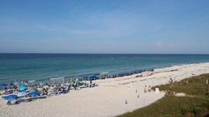 Une plage avec des parasols et des chaises longues, un ciel dégagé et l’océan.