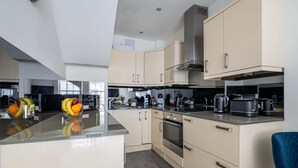 Une cuisine moderne dotée d’un îlot central, d’appareils électroménagers en acier inoxydable et de meubles de couleur claire.