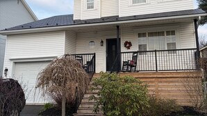 A two-story house with a front porch, a garage, and a small garden area. - Entire Apartment in Bedford (Bedford)
