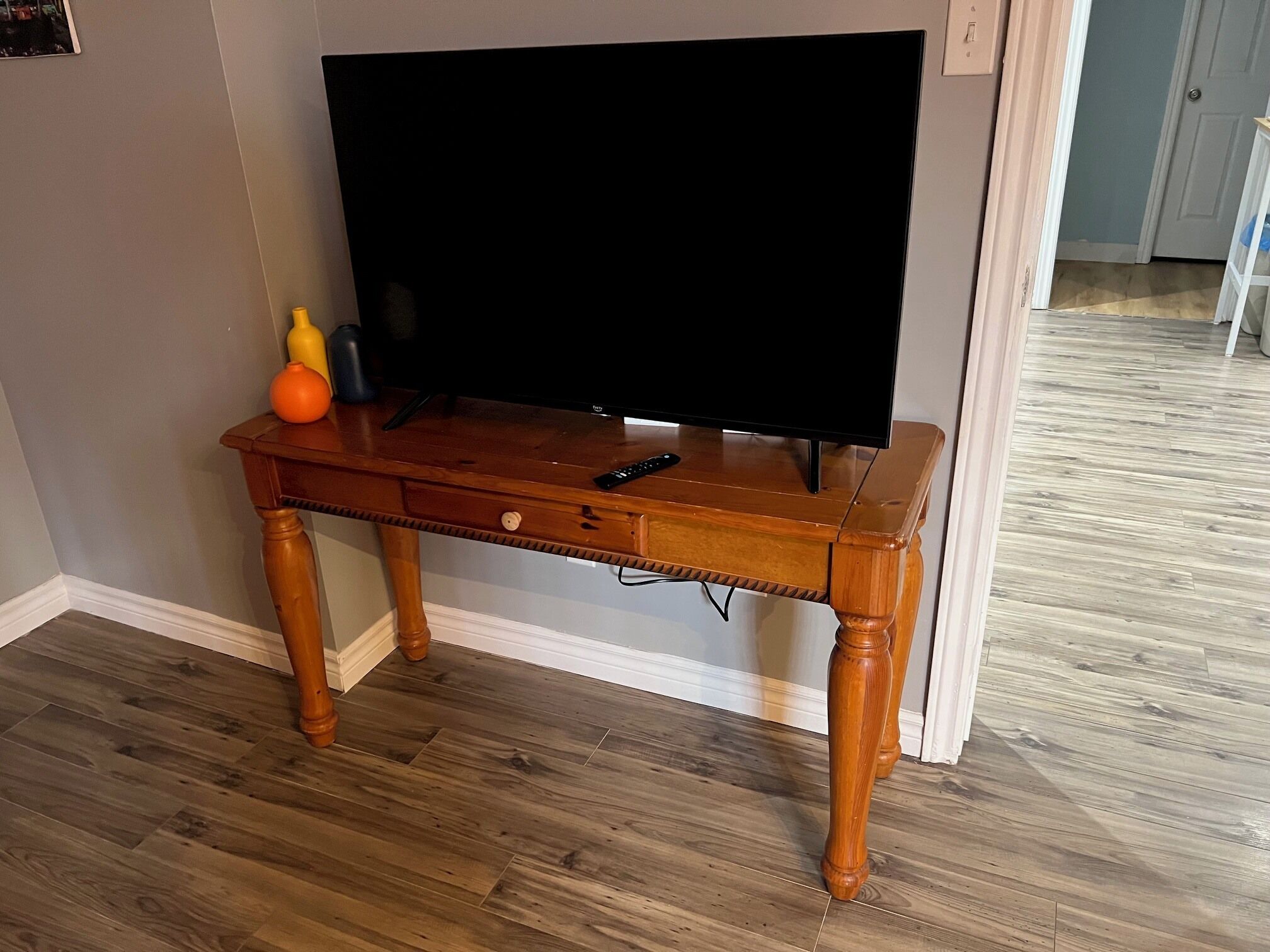 Un mueble de televisión de madera con un televisor de pantalla plana, un control remoto y un pequeño objeto naranja encima.