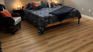 A bedroom with a bed, bedside tables, a window, and an air conditioning unit. - Entire Apartment in Bedford (Bedford)