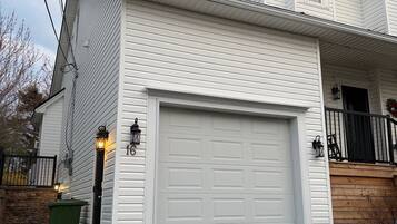 A two-story house with a white exterior, a garage, and a stone wall.