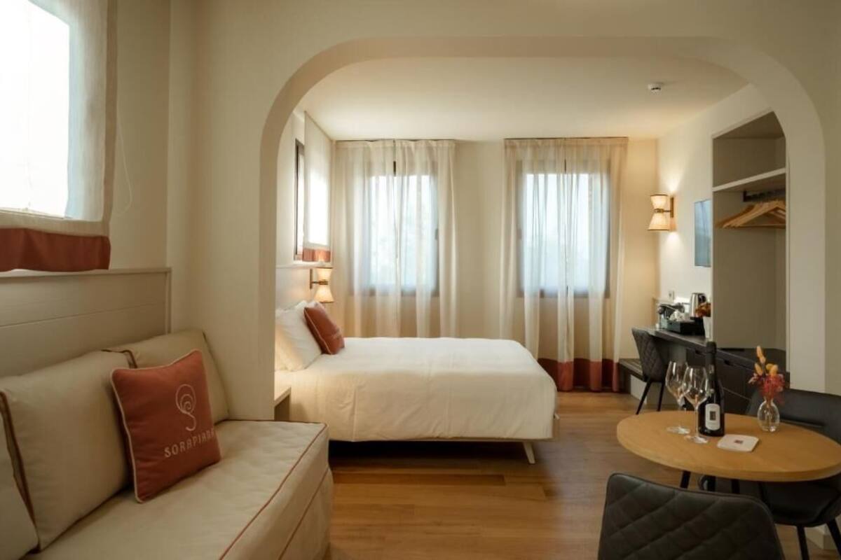 Habitación de hotel con cama, sofá, mesa de comedor con sillas y escritorio con silla.