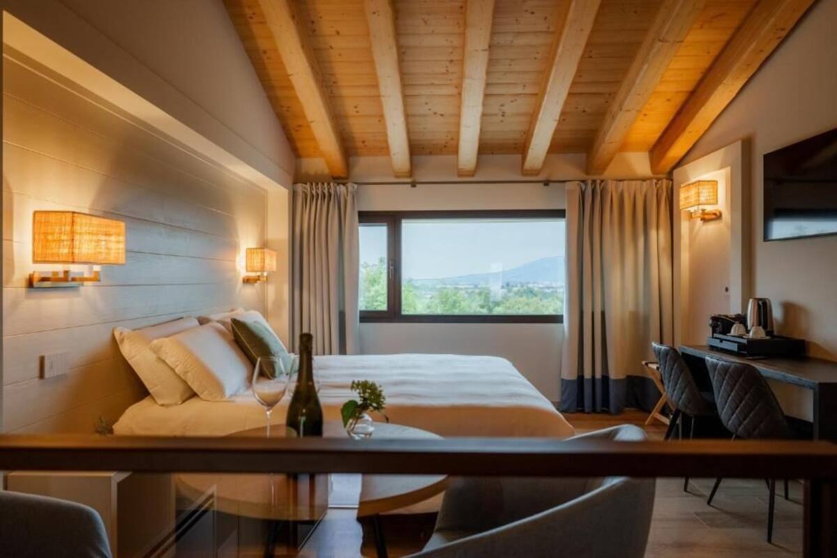 Un dormitorio con cama, lámparas de noche, un escritorio y vistas al exterior.
