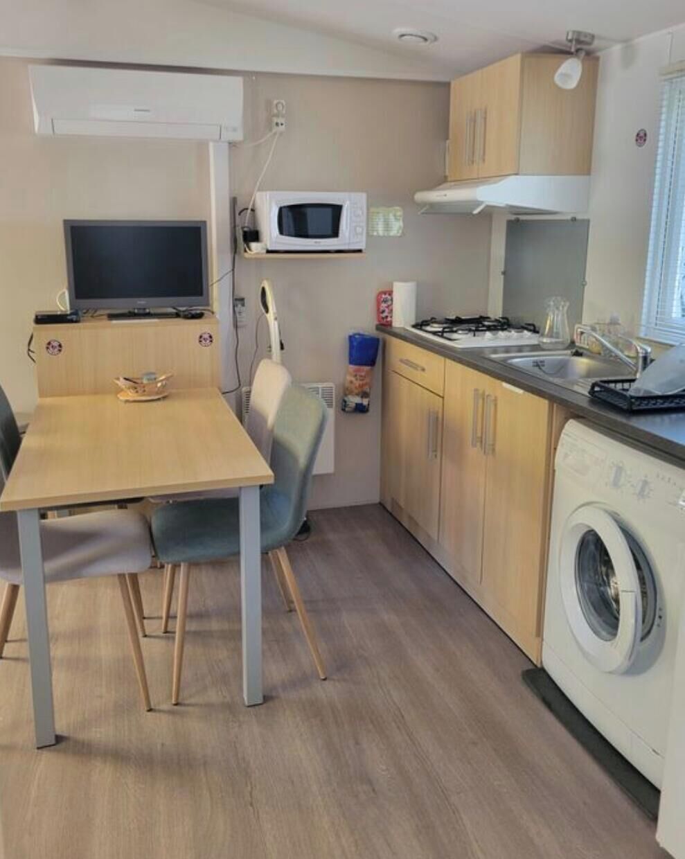 A compact kitchen with a microwave, stove, sink, and washing machine.