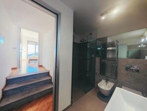 Une salle de bain moderne avec une douche à l’italienne en verre, un lavabo blanc et une baignoire.