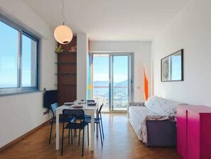 Un espace de vie moderne comprenant un coin repas, un canapé et une vue dégagée sur l’extérieur grâce à une porte vitrée.