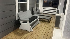 Een overdekte veranda met een bank en twee comfortabele stoelen.