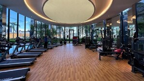 Et fitnesscenter med løbebånd, træningsmaskiner og et stort, rundt ovenlys.