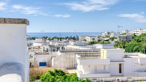 Une zone urbaine côtière avec des bâtiments blancs, quelques espaces verts et un ciel dégagé.