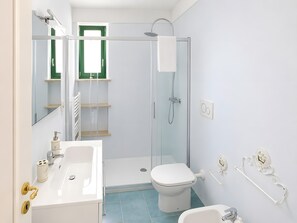 A modern bathroom with a shower, toilet, sink, and a mirror.