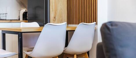 A modern dining area with a wooden table and white chairs.