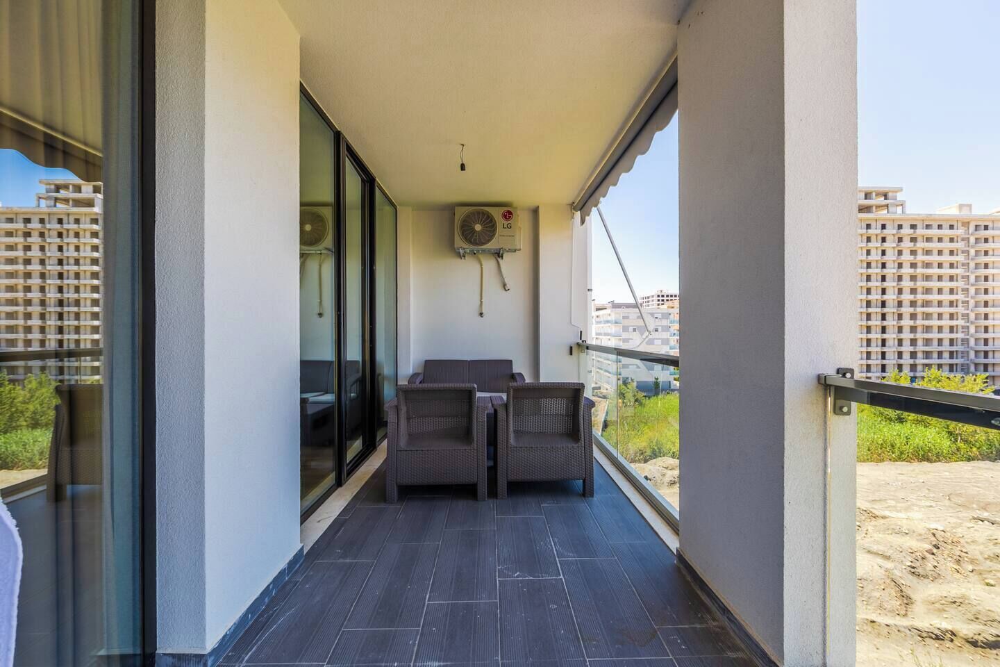Un balcon avec deux fauteuils en osier, une petite table et un ventilateur de plafond.