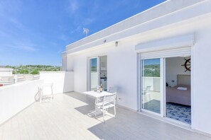 A modern apartment with a balcony, a dining area, and a bedroom with a sliding door.