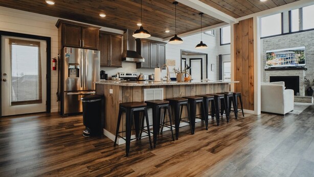 Eine moderne Küche mit Holzschränken, Edelstahlgeräten und einer Bar mit Hockern.