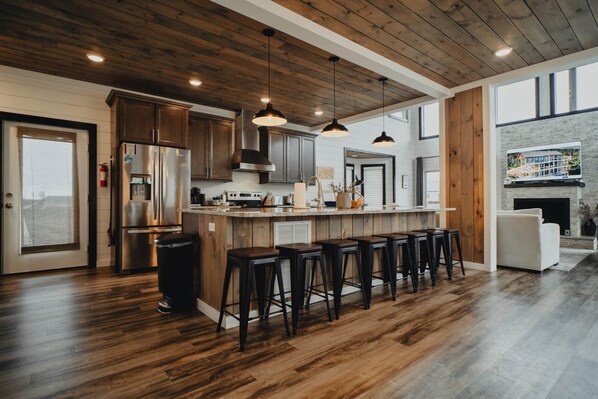 Eine moderne Küche mit Holzschränken, Edelstahlgeräten und einer Bar mit Hockern.