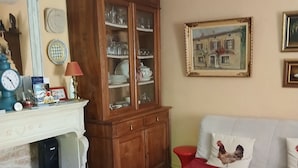 A living room with a fireplace, a cabinet with glass doors, a sofa with red cushions, and a patterned rug. - An 18th-century tower in the heart of the Haut-Beaujolais region (Deux-Grosnes)