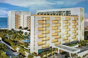 A multi-story hotel with a pool area and a view of the ocean.