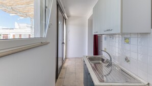 Eine schmale Küche mit Fenster, Spüle und Schränken.