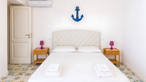 Ein Schlafzimmer mit einem Bett, zwei Nachttischen, einer Tür, einer Klimaanlage und einer Wanddekoration.