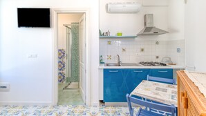 Une cuisine de taille réduite, équipée d’un téléviseur, d’un évier, d’une cuisinière et de meubles de rangement bleus.
