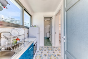 A narrow kitchen with a window, a sink, and a door leading to a bathroom. - Seafront Studio with Balcony in Castro di Lecce (Castro)