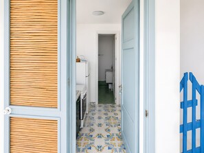 A hallway with a patterned floor, a door with a blue frame, and a blue gate on the right. - Seafront Studio with Balcony in Castro di Lecce (Castro)