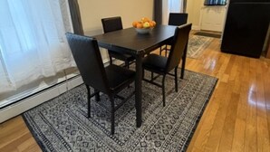 Un coin repas avec une table, des chaises et un panier de fruits.