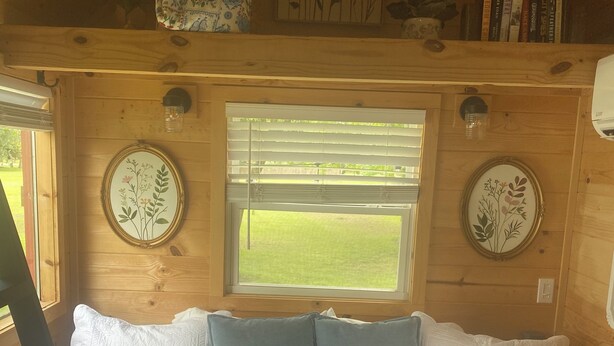 A cozy room with a bed, a window, and a bookshelf. - Cozy 1-bedroom cabin in amazing Winnie with AC (Winnie)