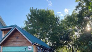 A small wooden cabin with a green roof, a porch, and a brick pathway leading to it. - Cozy 1-bedroom cabin in amazing Winnie with AC (Winnie)