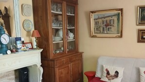 Ein Wohnzimmer mit Kamin, einem Schrank mit Glastüren, einer Couch mit roten Kissen und einem gemusterten Teppich.
