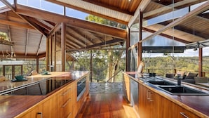 Una cucina moderna con mobili in legno, un'isola centrale e ampie finestre con vista sul paesaggio circostante.