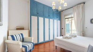 Un dormitorio con cama, una silla, un armario y una araña.