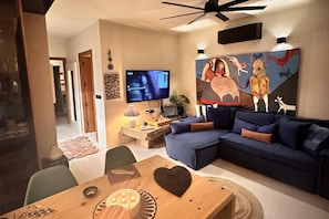 A living room with a sofa, a coffee table, a TV, and a painting on the wall.