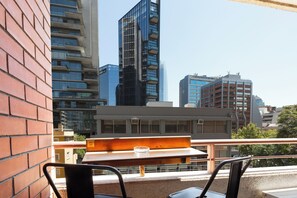 Ein Balkon mit Tisch und Stühlen mit Blick auf eine Skyline moderner Gebäude.