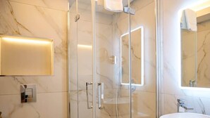 A modern bathroom with a glass-enclosed shower, a marble-tiled wall, a white sink, and a mirror. - Experience Dingle @ Main Street - Room 3 (Dingle)