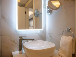 A bathroom with a large oval sink, a wall-mounted mirror, and a towel rack. - Experience Dingle @ Main Street - Room 3 (Dingle)