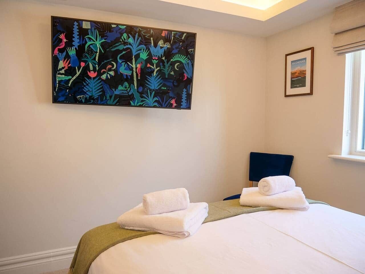 Habitación de hotel con dos camas, un cuadro en la pared, una ventana y una silla.
