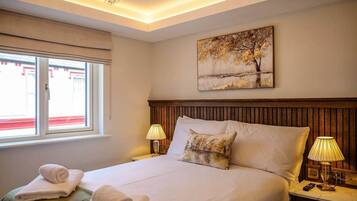 Habitación de hotel con una cama grande, dos lámparas de noche, un cuadro en la pared y una ventana con vistas.