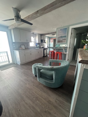 A modern kitchen with white cabinets, a stainless steel stove, and a ceiling fan.