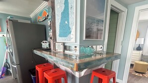 Eine Küche mit Barbereich, roten Barhocker, einem Kühlschrank und einer Karte an der Wand.