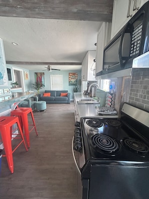 A kitchen with a stove, microwave, and red bar stools.