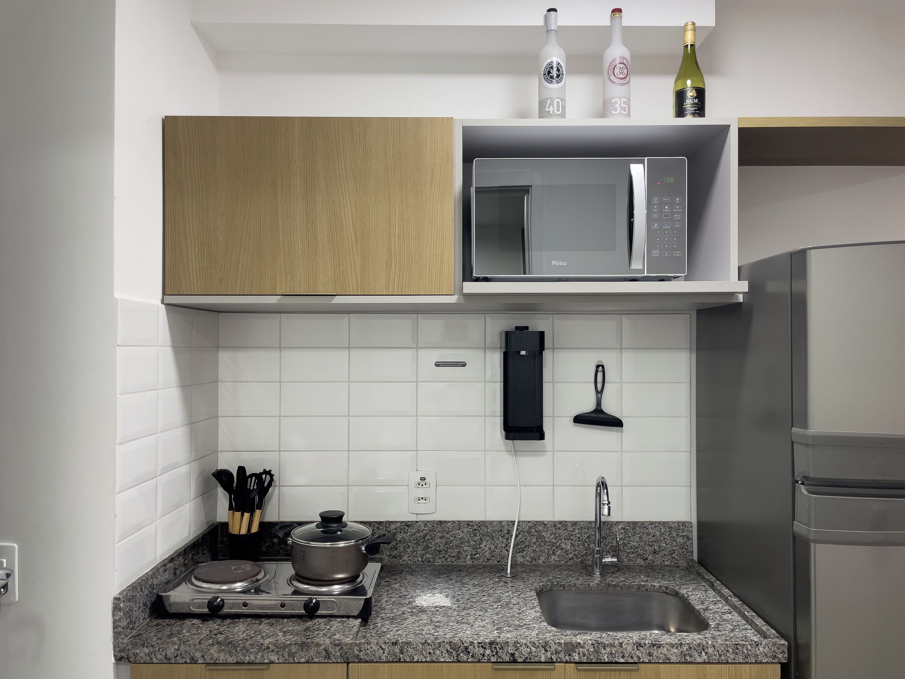 A kitchen with a microwave, a gas stove, a sink, and a refrigerator.