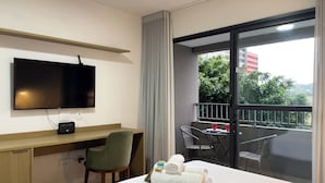 A hotel room with a bed, a desk with a chair, a TV, and a balcony with a table and chairs. - Today Butanã (São Paulo)