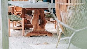 A rustic outdoor dining area with wicker furniture, a wooden table, and hanging wicker lamps. - Bleu guesthouse (Saint-François)
