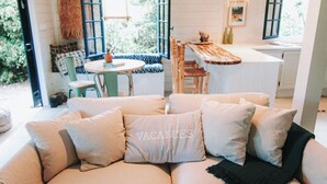A cozy living area with a sofa, a dining table, and chairs. - Bleu guesthouse (Saint-François)