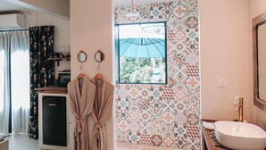 A bathroom with a patterned wall, a sink, a mirror, and a hanging robe rack. - Bleu guesthouse (Saint-François)